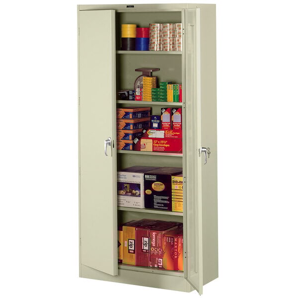 A Tennsco putty metal storage cabinet with shelves and boxes inside.