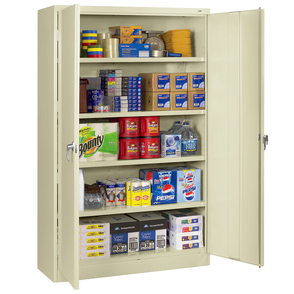 A Tennsco putty jumbo storage cabinet with solid doors and many items on the shelves.