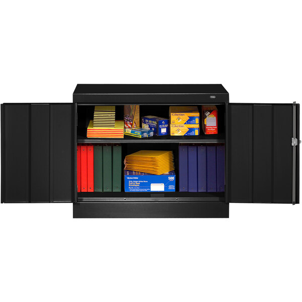 A black metal Tennsco storage cabinet with shelves full of books and boxes.