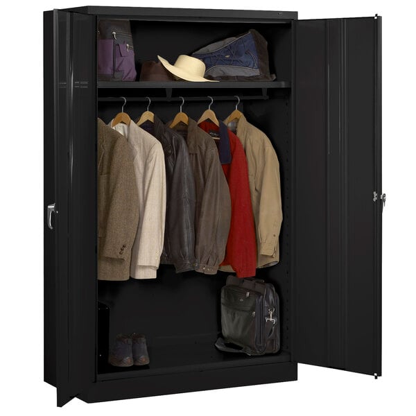 A black metal Tennsco jumbo wardrobe cabinet with solid doors and clothes and bags inside.