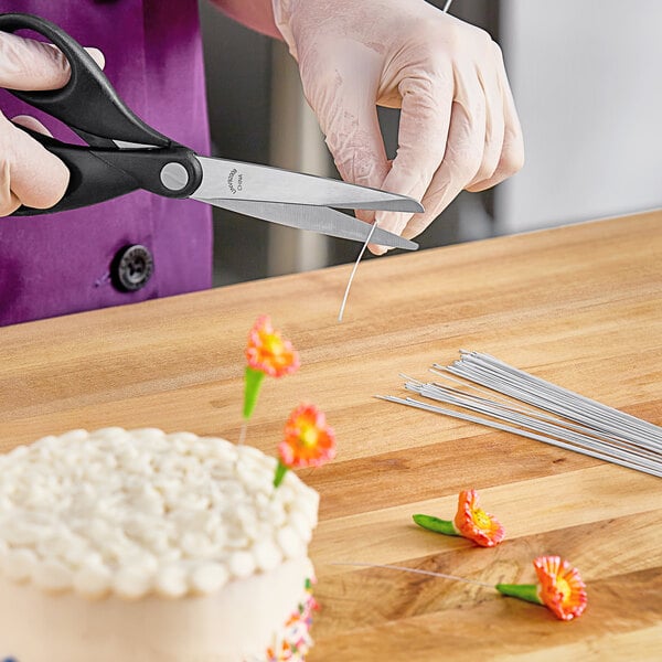 A person cutting white floral wire with scissors.