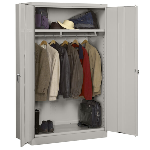 A light gray metal wardrobe cabinet with solid doors holding clothes and bags.