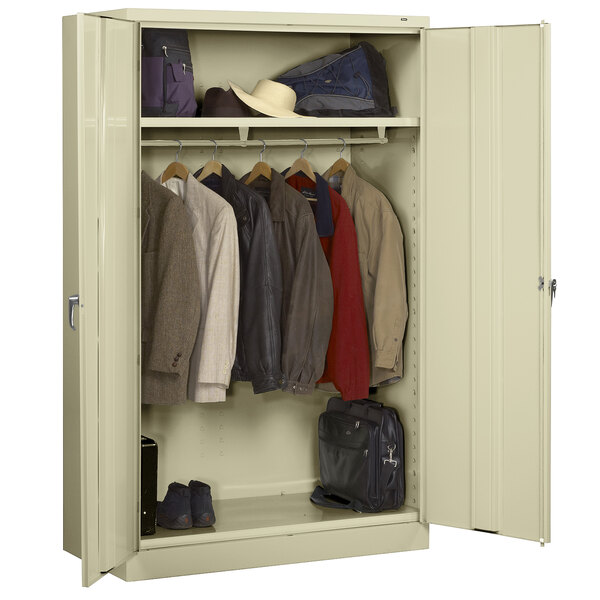 A Tennsco putty metal wardrobe cabinet with clothes and shoes inside.