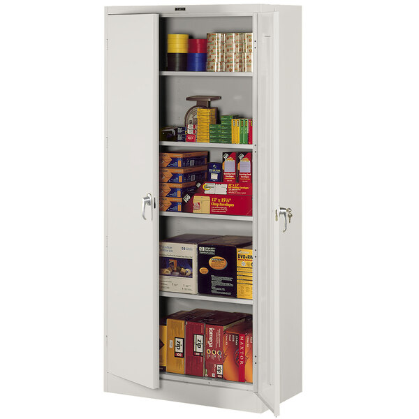 A light gray Tennsco storage cabinet with solid doors and shelves full of items.