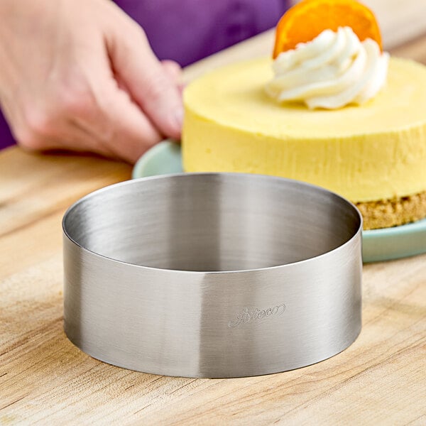 A yellow cake with a round metal ring on a wood surface.