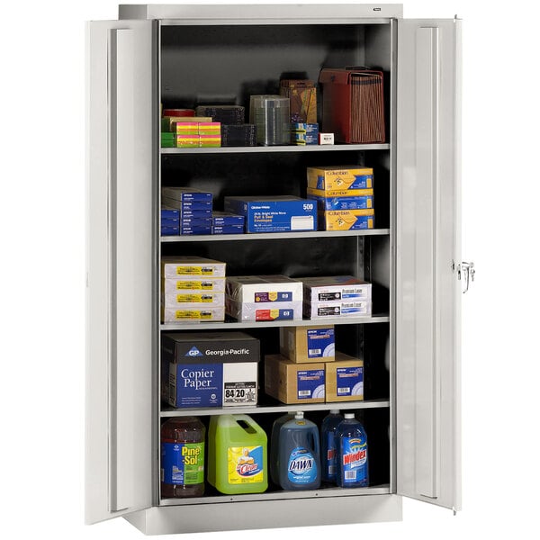 A light gray Tennsco storage cabinet with solid doors and items on shelves.