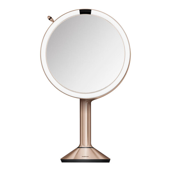 A round simplehuman rose gold sensor mirror on a stand.