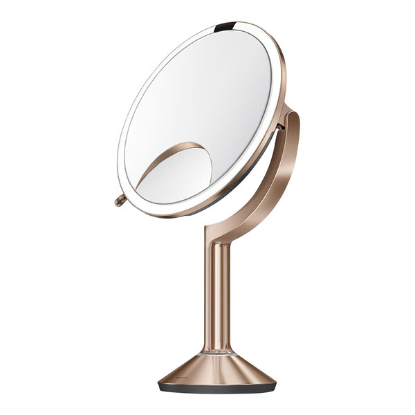 A simplehuman circular mirror on a rose gold stand.
