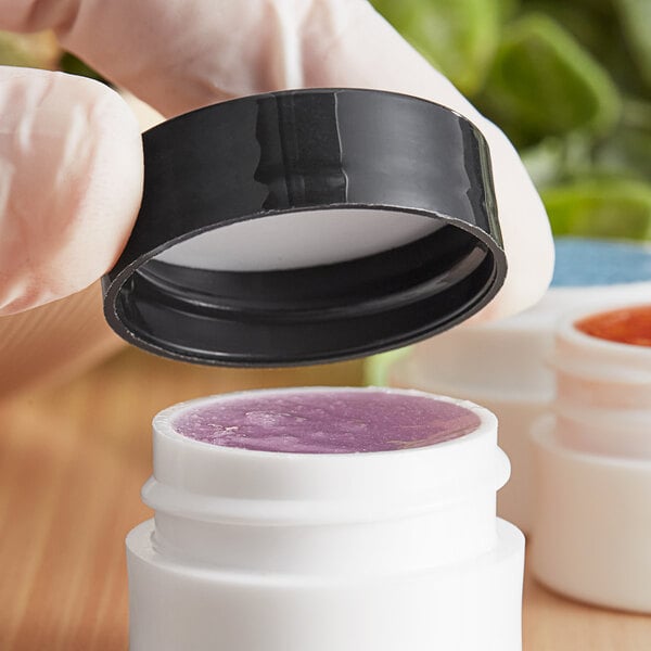 A hand holding a 33/400 black plastic lid over a white container.