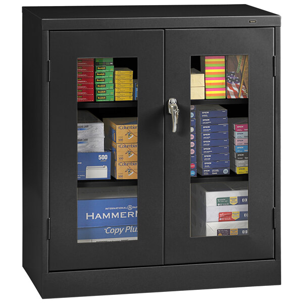 A black Tennsco storage cabinet with C-Thru doors holding books and files.