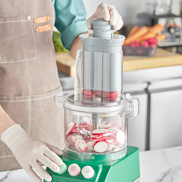 A person using an AvaMix clear plastic batch bowl with chute lid on a food processor to make candy.