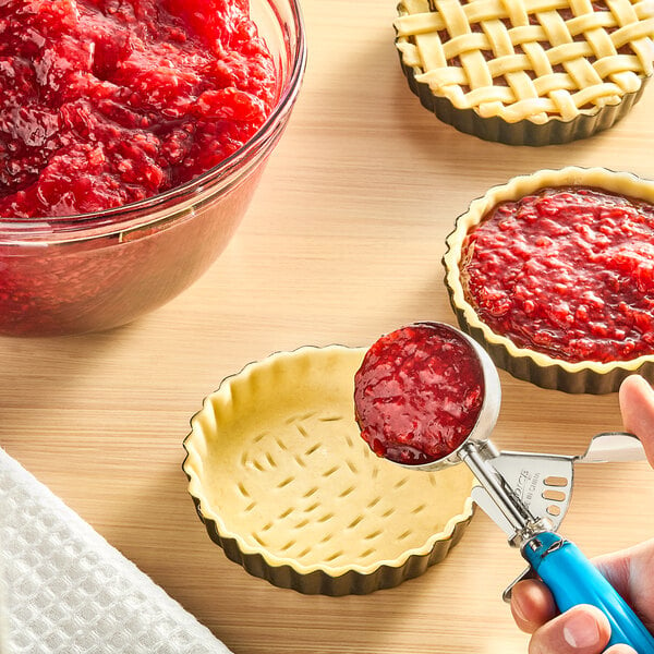 A hand using a spoon to scoop Lucky Leaf Red Raspberry Pie Filling from a bowl.