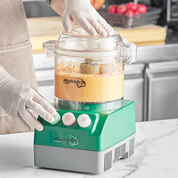 A person using an AvaMix food processor on a counter.