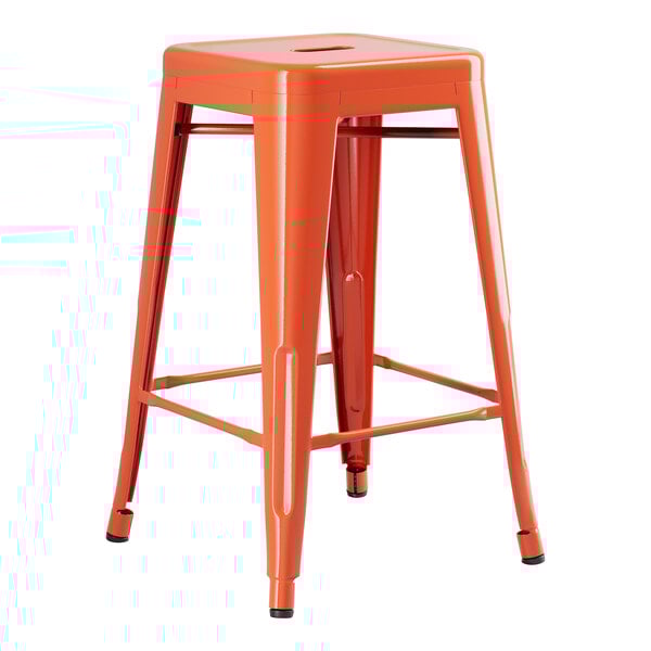 An orange Lancaster Table & Seating backless outdoor counter height stool with metal legs.