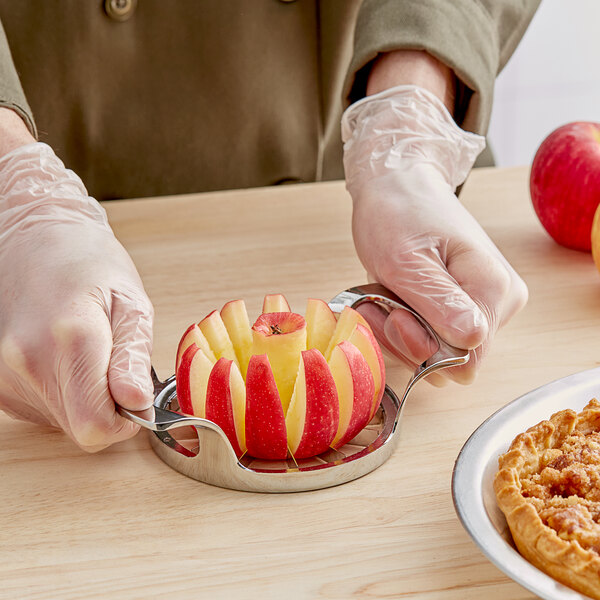 A person in gloves using a Choice apple corer to slice a red apple.