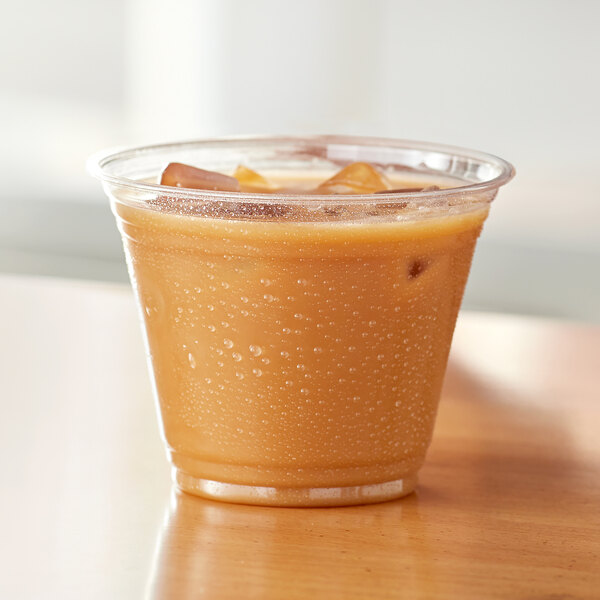 A Choice clear plastic squat cup filled with iced coffee on a table.