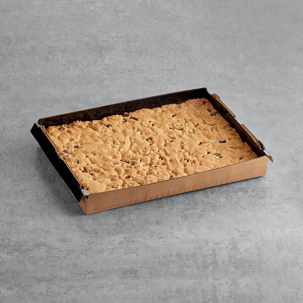 A brown box from Root Nine Baking Co. with a cookie inside on a gray surface.