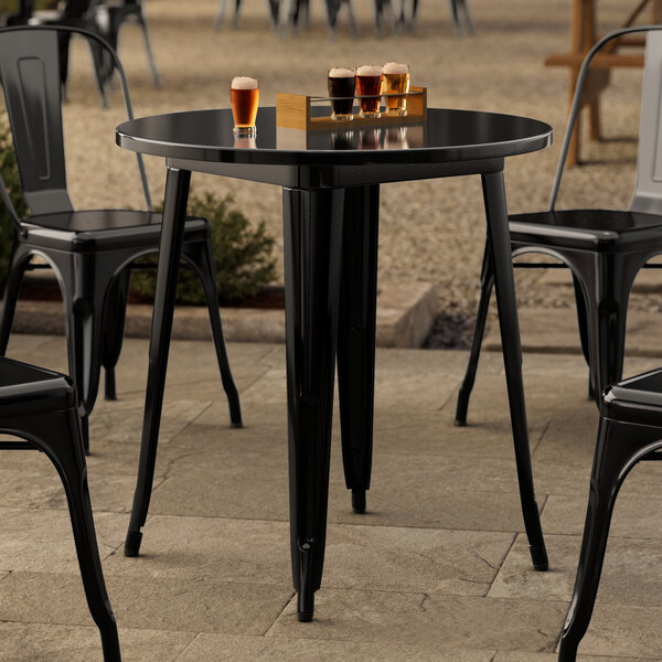 A Lancaster Table & Seating black metal outdoor table with black chairs on a patio.