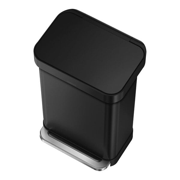 A simplehuman matte black rectangular step-on trash can with a silver lid.