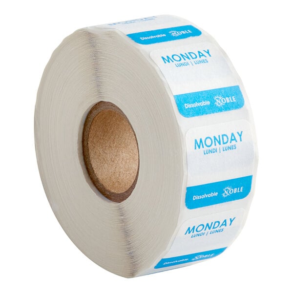 A roll of white labels with blue text that says "Monday" with the product name "Noble Products Monday 1" Dissolvable Day of the Week Label" on it.