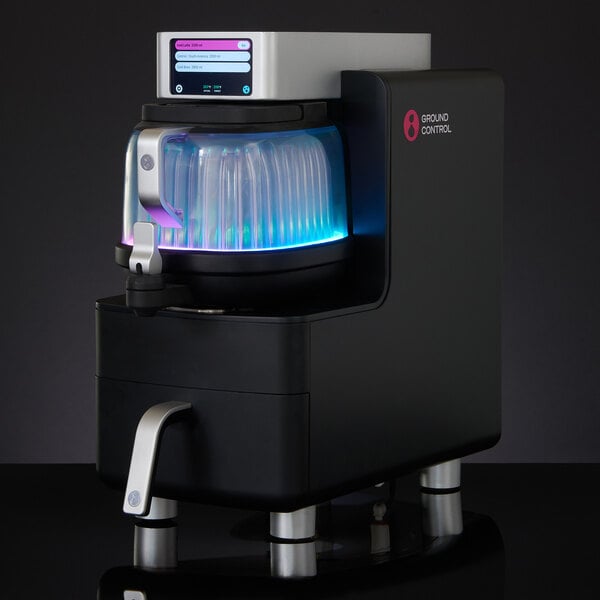 A black and silver Ground Control Smart Dispenser automatic coffee brewer with a blue light.