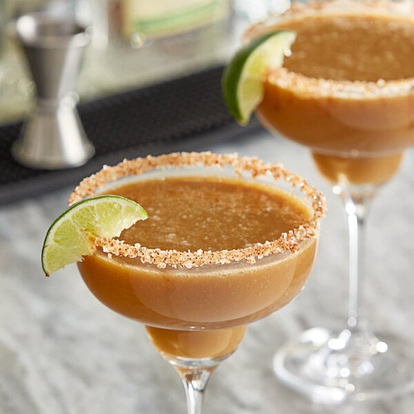 A brown drink in a glass with a lime wedge on the rim.