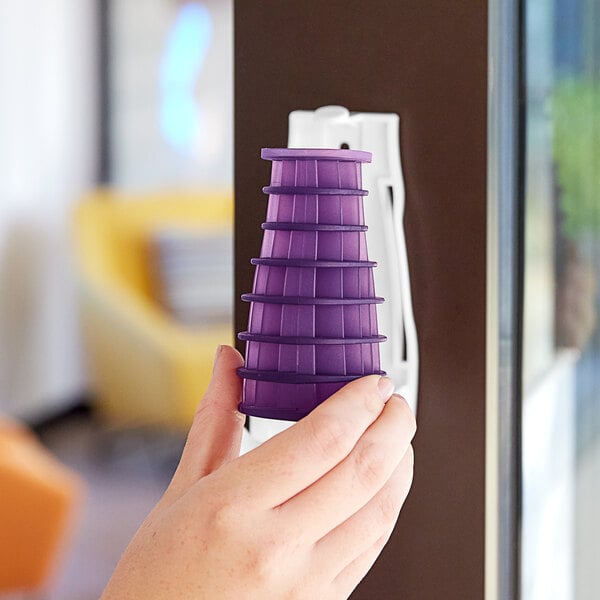 A hand holding a purple plastic Fresh Products Eco-Air air freshener refill.