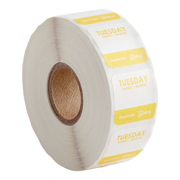 A roll of white and yellow Noble Products labels with the word "Tuesday" on them.