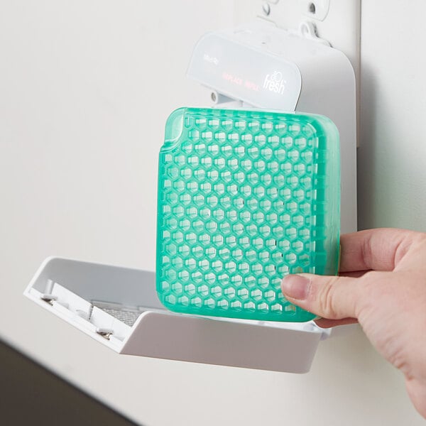 A person's hand holding a green and white Ourfreshe Cucumber Melon air freshener refill container.