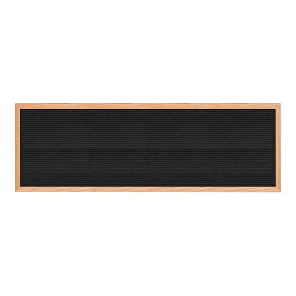 A black countertop menu letterboard with a light oak wood frame.