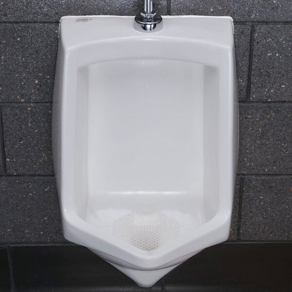 A white ceramic urinal with a clear mango-scented urinal screen placed at the bottom.