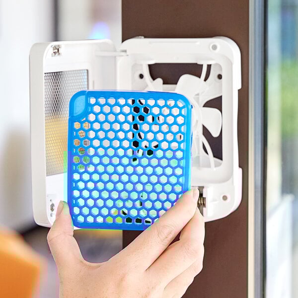 A hand holding a blue plastic cover with a blue and white hexagonal grid inside.