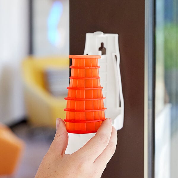 A hand holding an orange plastic cone with many holes.