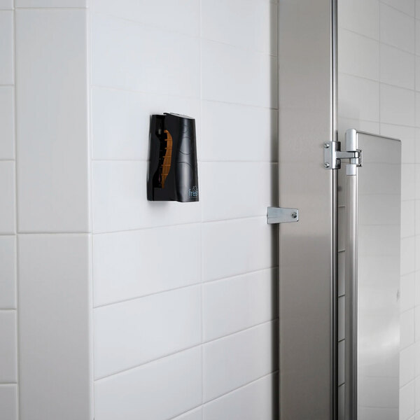 A black passive air freshener cabinet mounted on a white tiled wall in a restroom.
