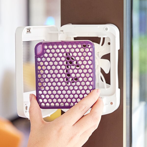 A hand holding a purple Ourfresh air freshener refill in a purple plastic container.