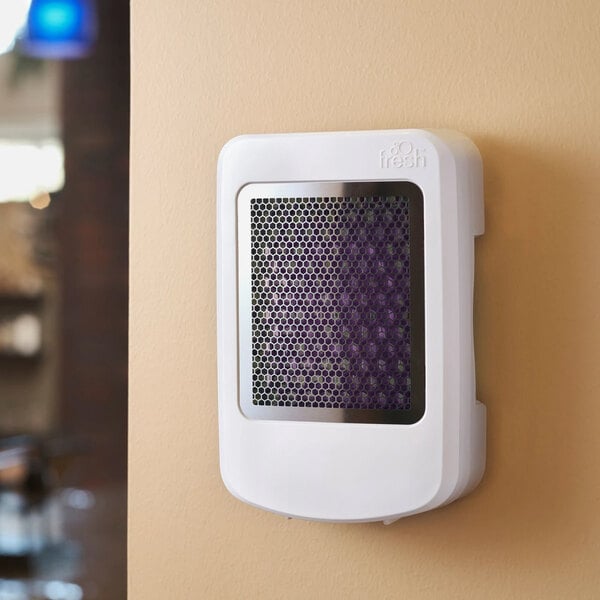 A wall-mounted white air freshener unit with a black mesh front panel.