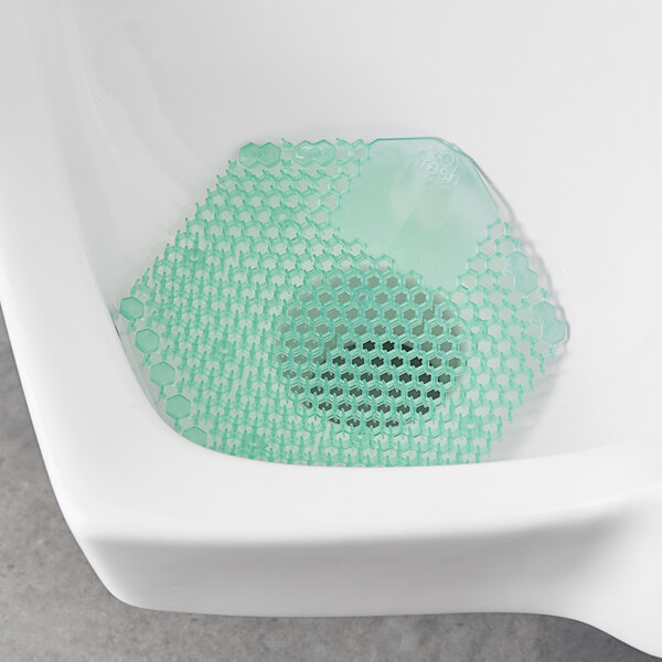 A green plastic mesh with holes in a urinal.