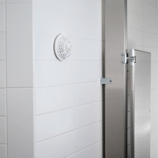 A white air freshener dispenser mounted on a tiled wall.