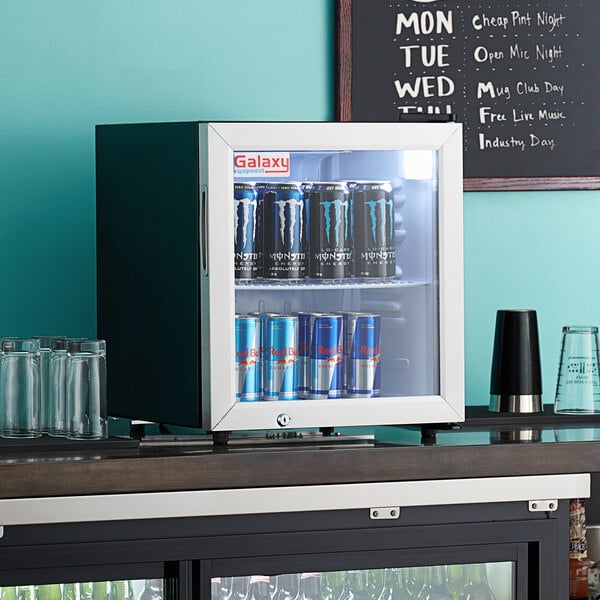 A Galaxy black countertop refrigerated merchandiser with cans of energy drinks.