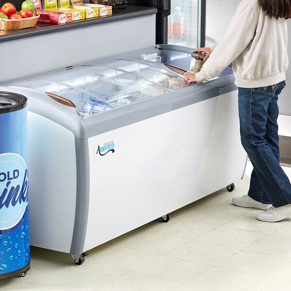 A woman standing near an Avantco curved glass top display freezer.