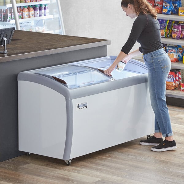 A woman opening the curved glass door of an Avantco custom ice cream freezer.