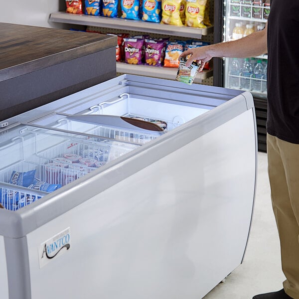 A person standing next to an open Avantco custom vinyl glass top display freezer.