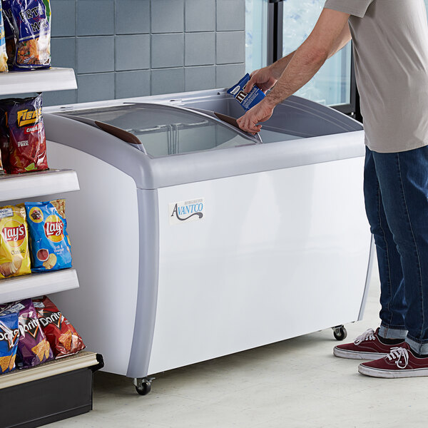 A man opening the curved glass door of an Avantco display freezer.