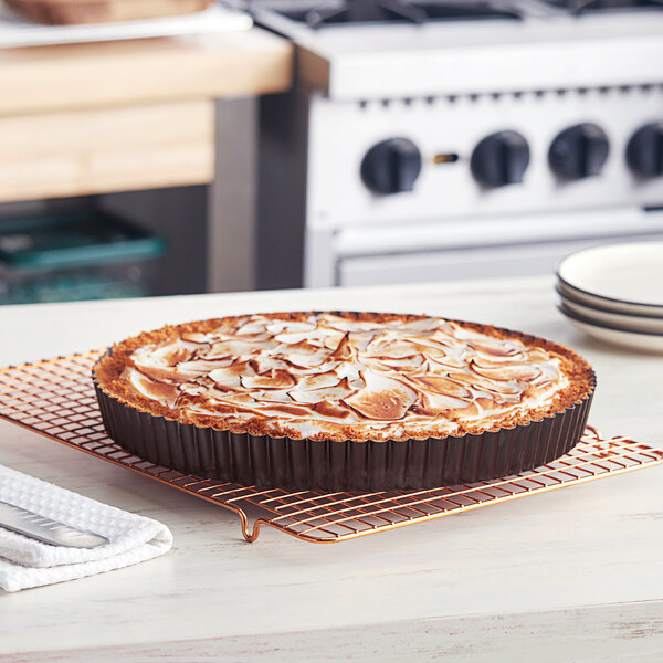 A pie in a Gobel round fluted tart pan on a cooling rack.