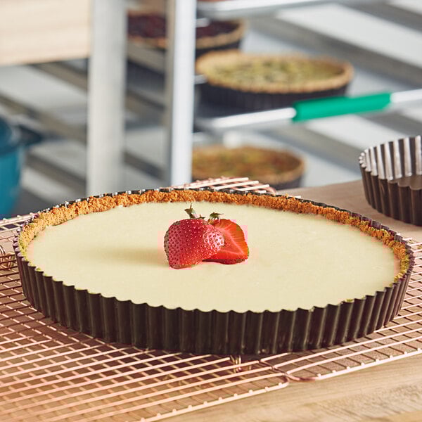A round tart with a strawberry on top of it.
