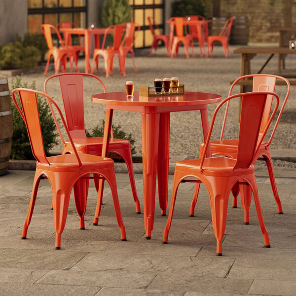 A Lancaster Table & Seating outdoor table with orange chairs.