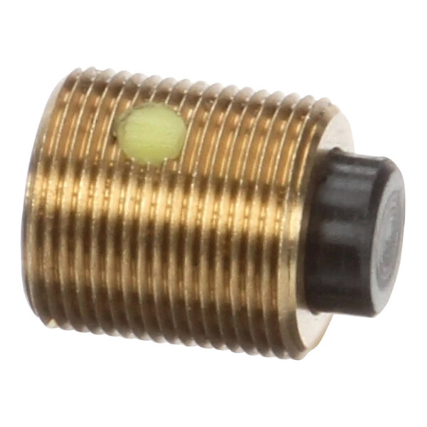 A brass threaded plug with a yellow dot on the end of a screw.