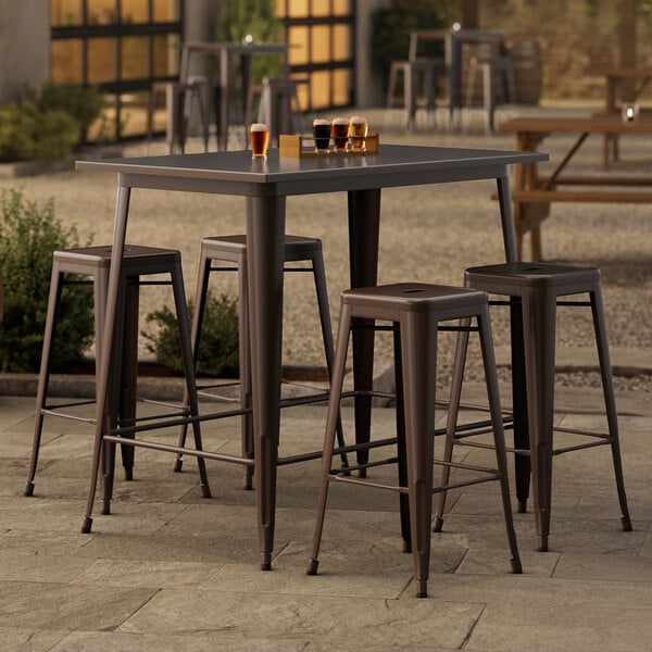 A Lancaster Table & Seating bar height outdoor table with four barstools on a patio.