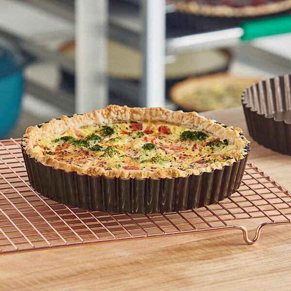 A quiche in a Gobel round fluted deep tart pan on a cooling rack.