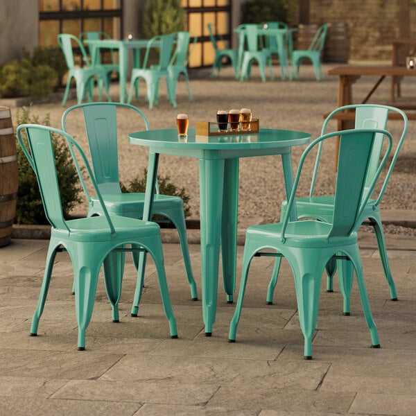 A Lancaster Table and Seating outdoor table with green chairs on a patio.